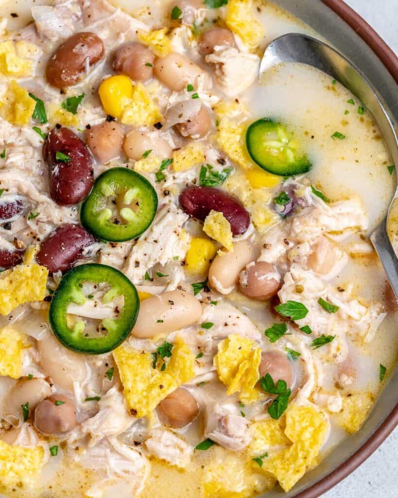 close up of white chili in a bowl topped with sliced jalapenos