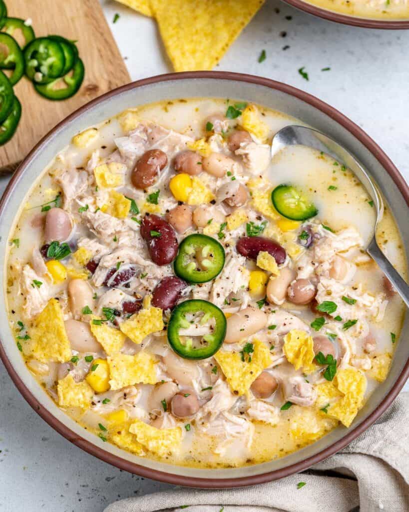 round bowl of white chicken chili with beans and spoon in bowl
