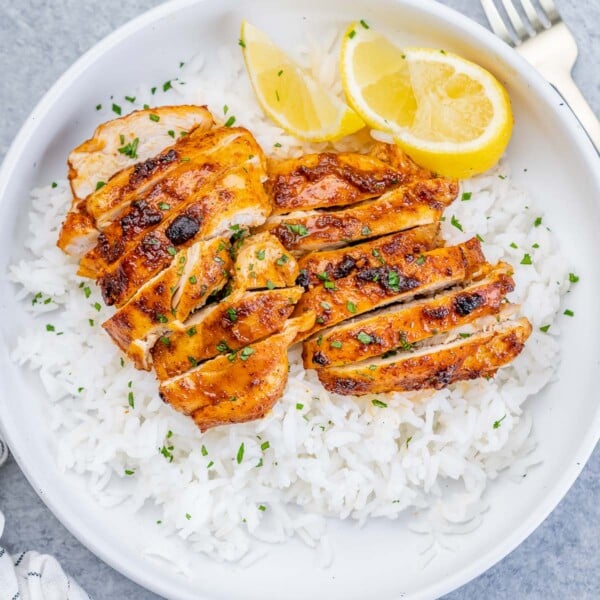 top view of a round white bowl with steamed white rice and sliced air-fried boneless chicken thighs