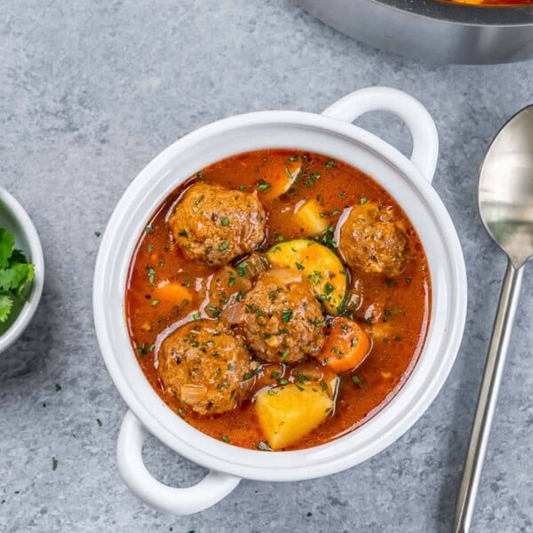 top view of a white bowl with handles that has Mexican meatball soup that is tomato based