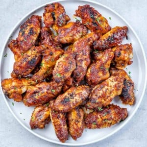 baked chicken wings on a round white plate.