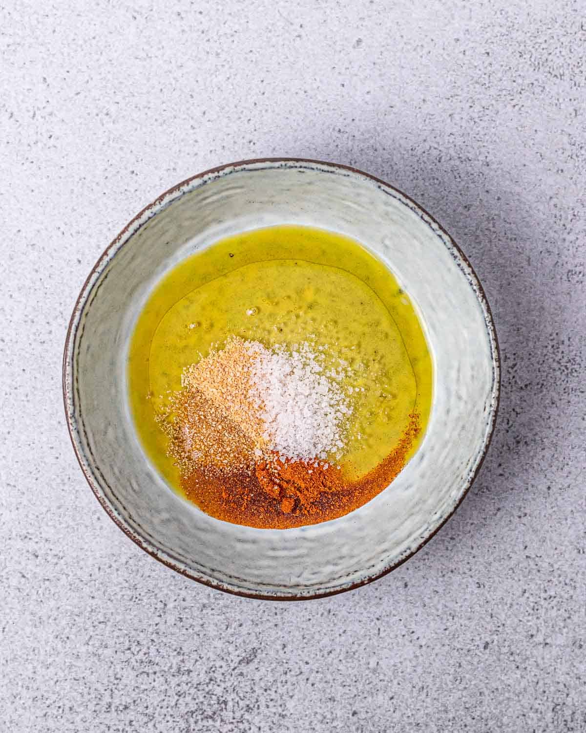 Mixing seasonings with oil in a small bowl.