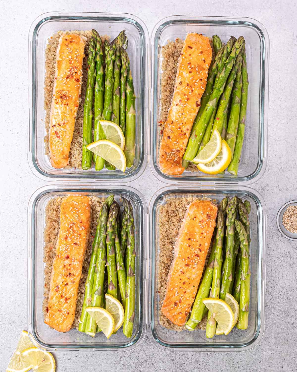 Assembling 4 bowls with salmon, asparagus, and quinoa.