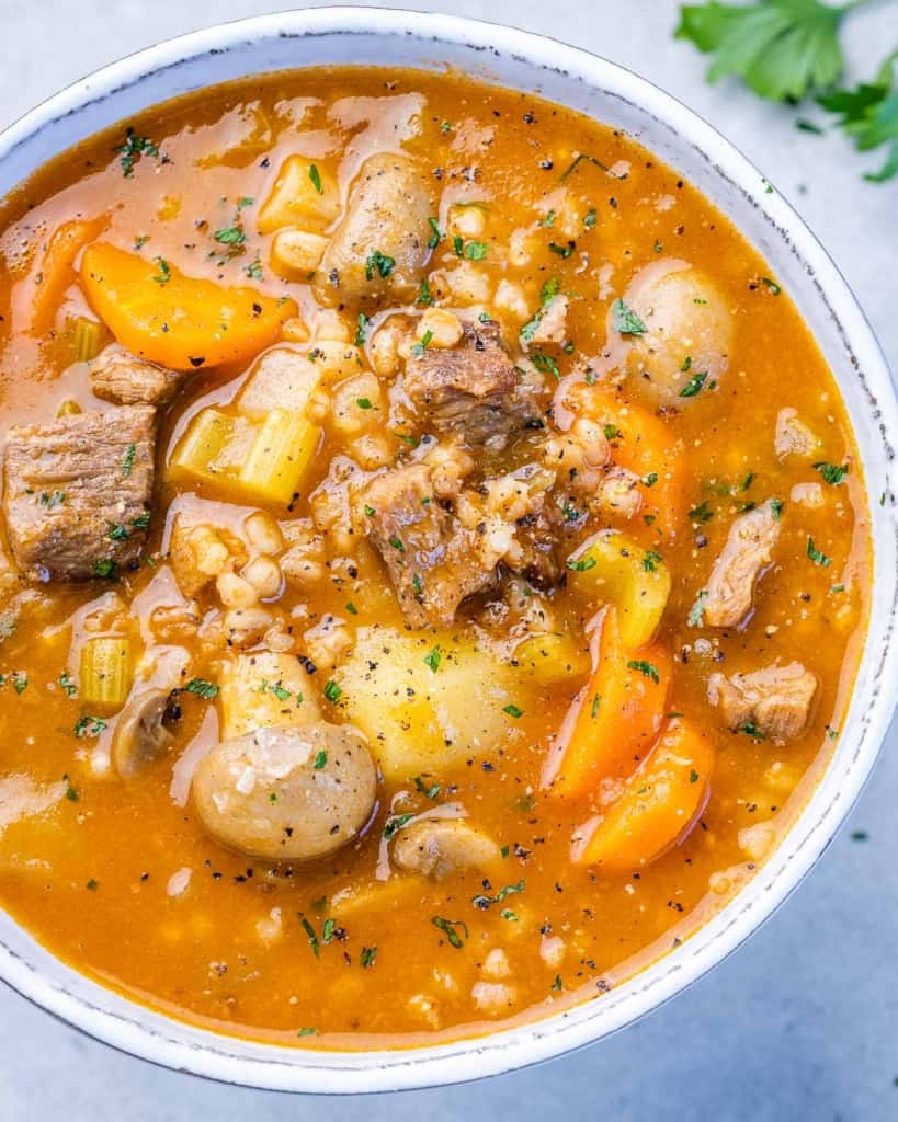 top close up view of barley soup in a white bowl