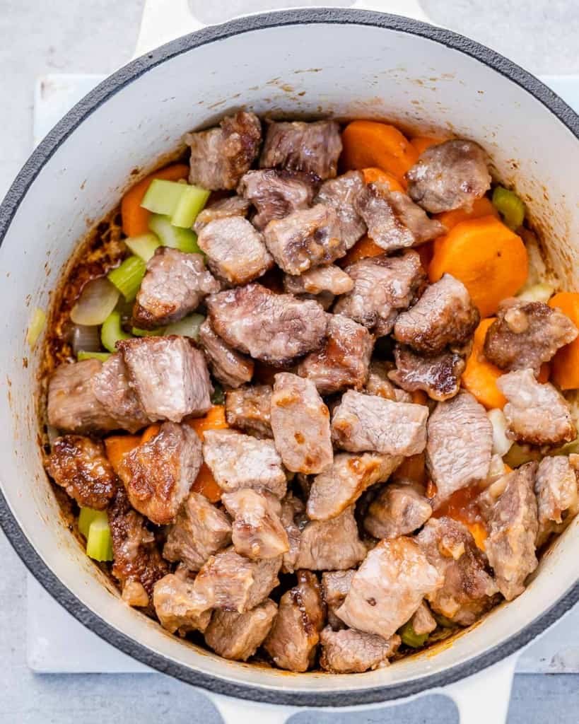 sauteed veggies in a pot topped with cooked beef chuncks