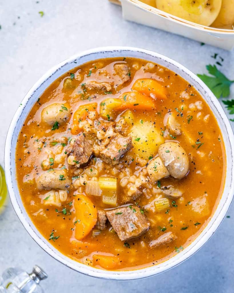 top view of barley and beef soup in a white bowl