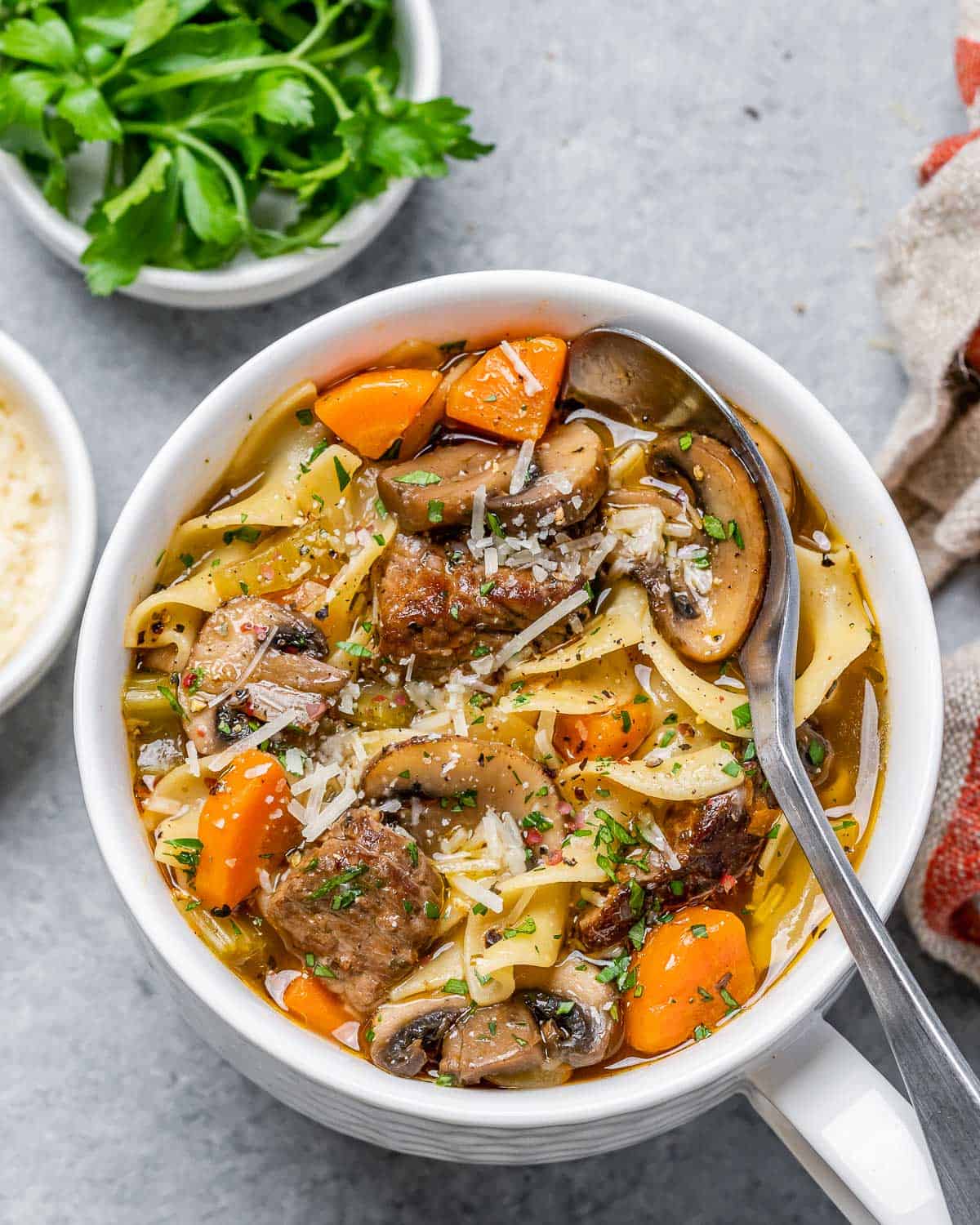 Beef noodle soup served in a white bowl with a spoon.