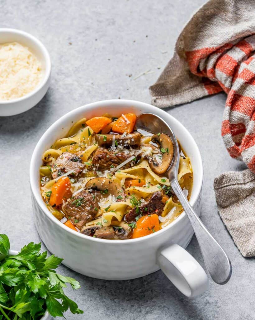 Beef noodle soup in a white bowl with a spoon.