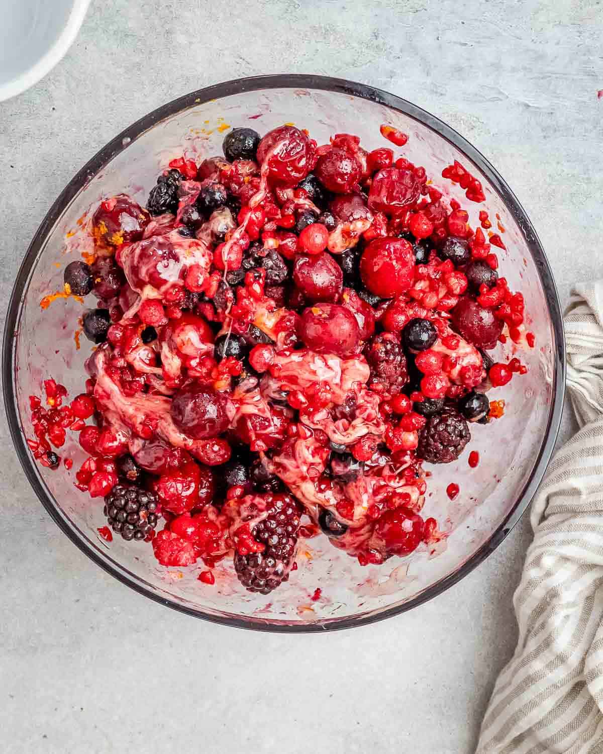 frozen berries mixed in with the honey orange juice and zest in a round clear bowl