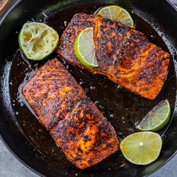 top view two pan cooked salmon filet with lime slices