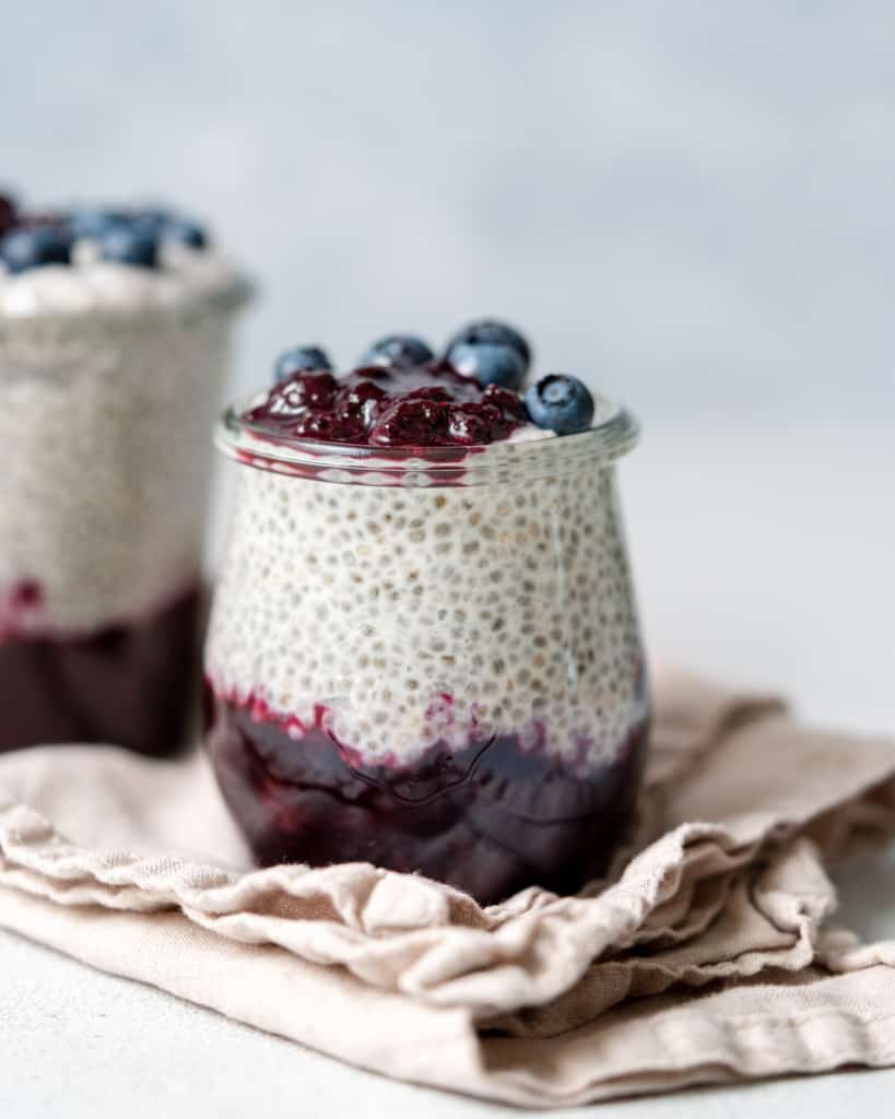 close up side shot of chia pudding in a jar with blueberry jam at the bottom