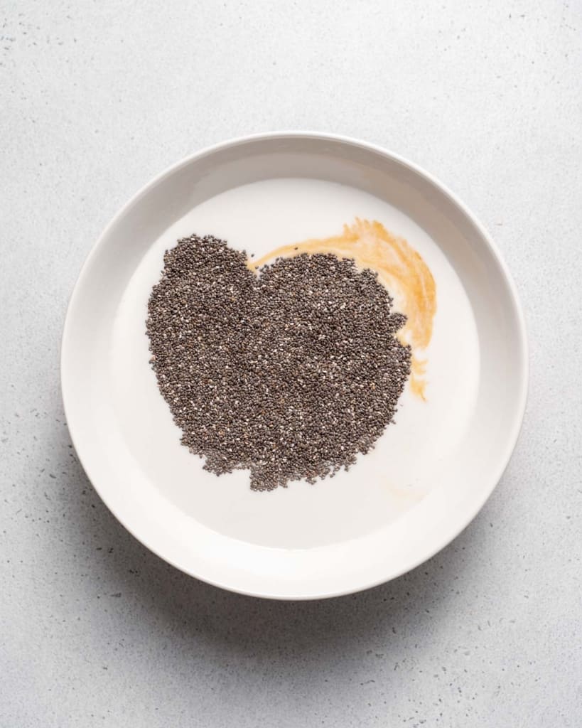 Chia seeds mixed with milk, vanilla and honey in a white bowl.