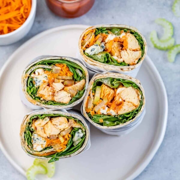 half chicken sandwich wraps on a white round plate.