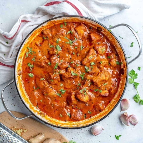 Top view of a skillet with butter chicken topped with chopped fresh cilantro.