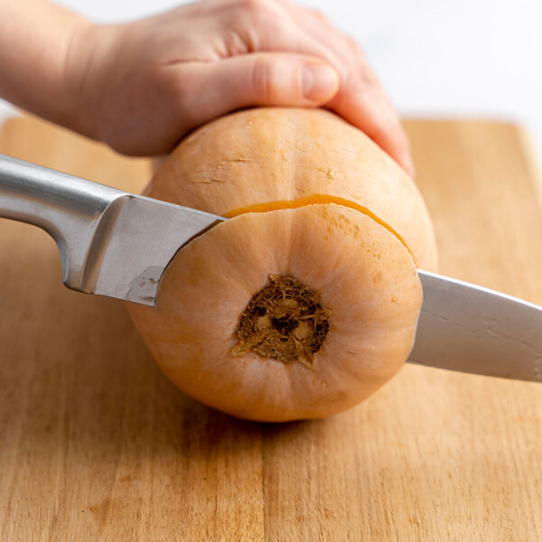 side shot of how knife slicing the bottom end of the butternut squash