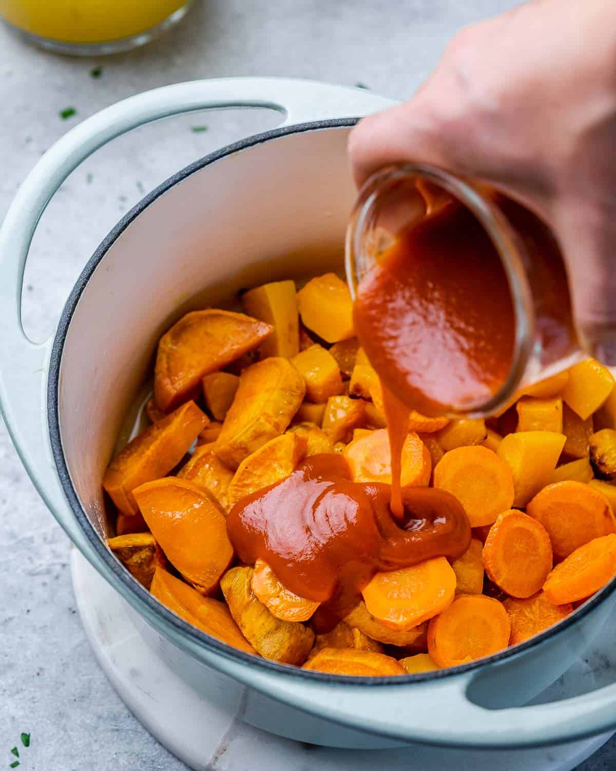 enchilada sauce being poured over the post with roasted veggies 