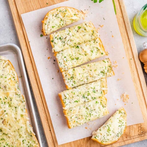 garlic bread sliced lengthwise on a cutting board.