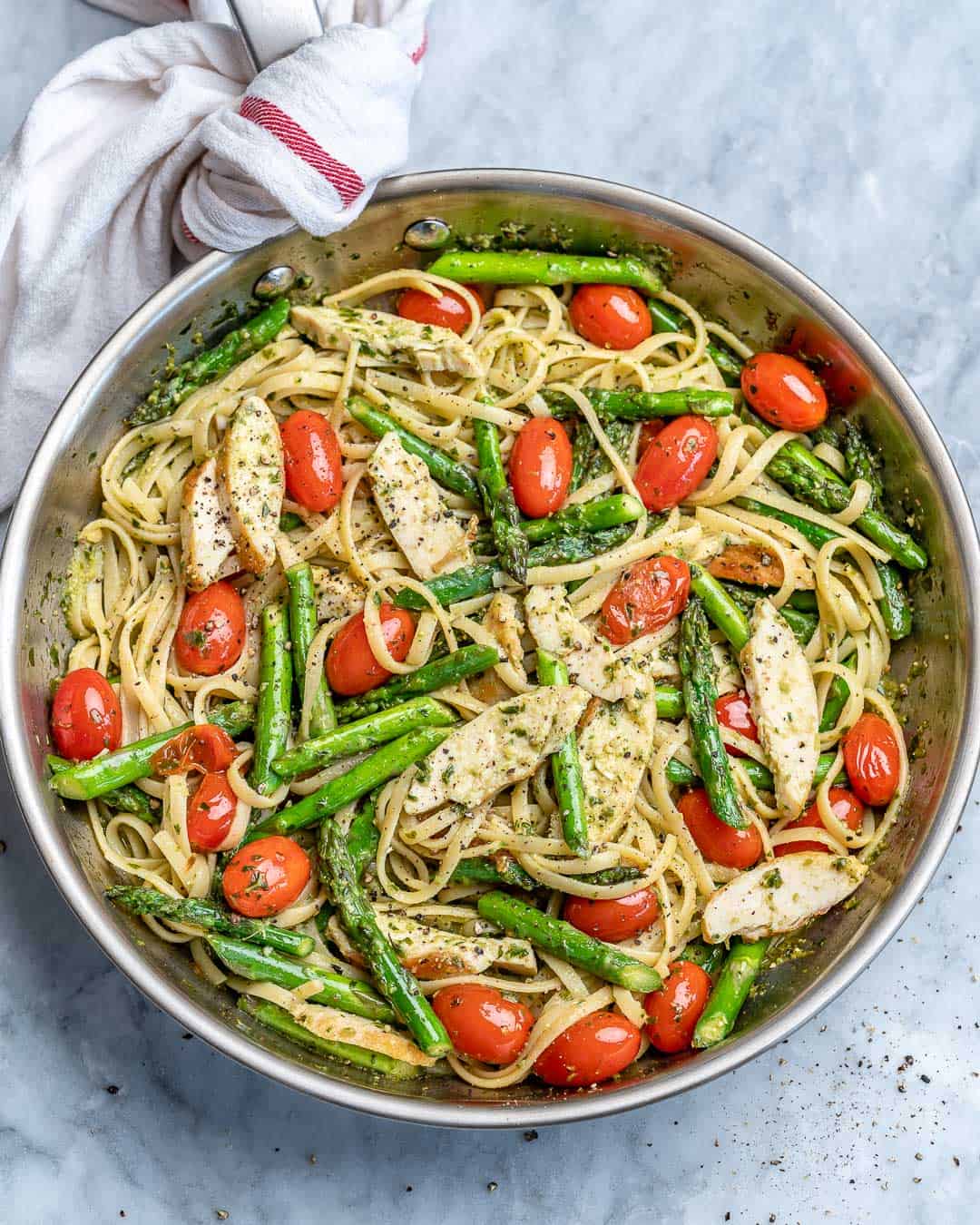 top view of stainless steel skillet with chicken asparagus pasta with cherry tomatoes