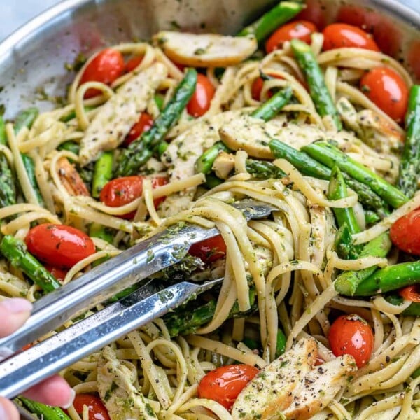 tong grabbing some chicken asparagus pasta from pan