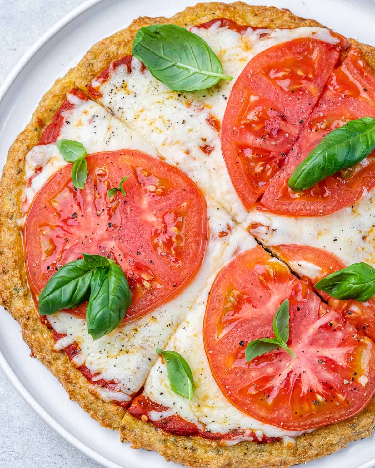 chicken crust pizza sliced into 4 sections and topped with melted cheese and sliced tomatoes.