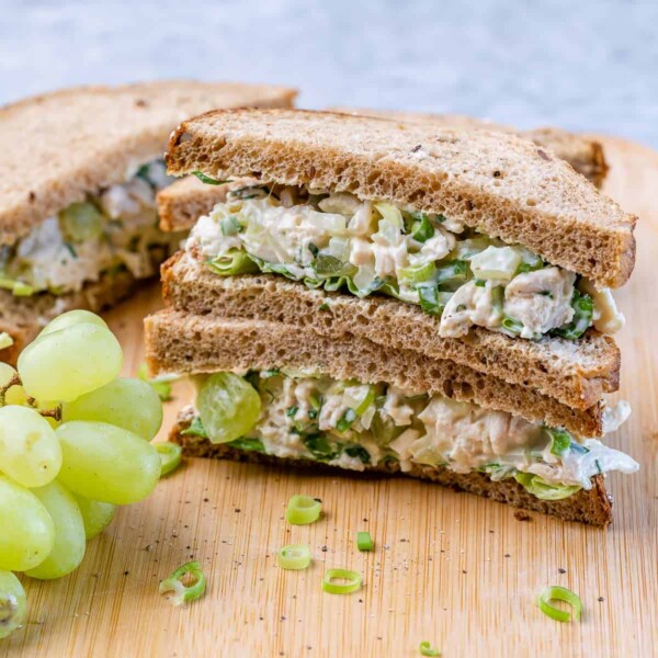 chicken sandwich stacked on each other with a side of grapes on the bottom left.