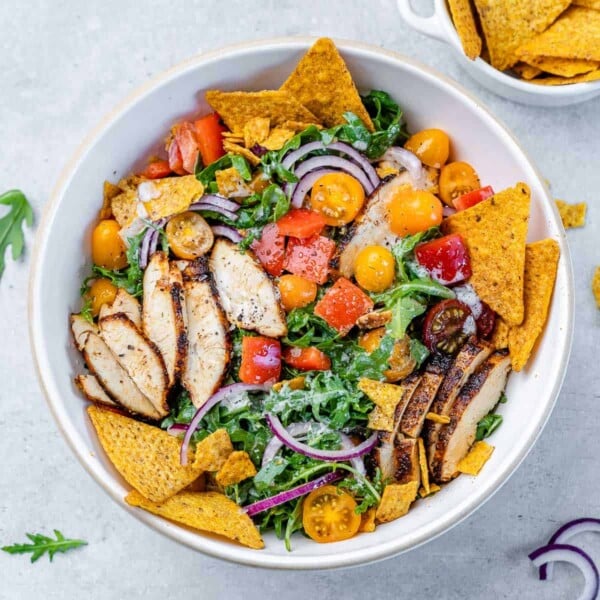 top view taco salad topped with sliced of grilled chicken breast and tortilla chips in a white bowl