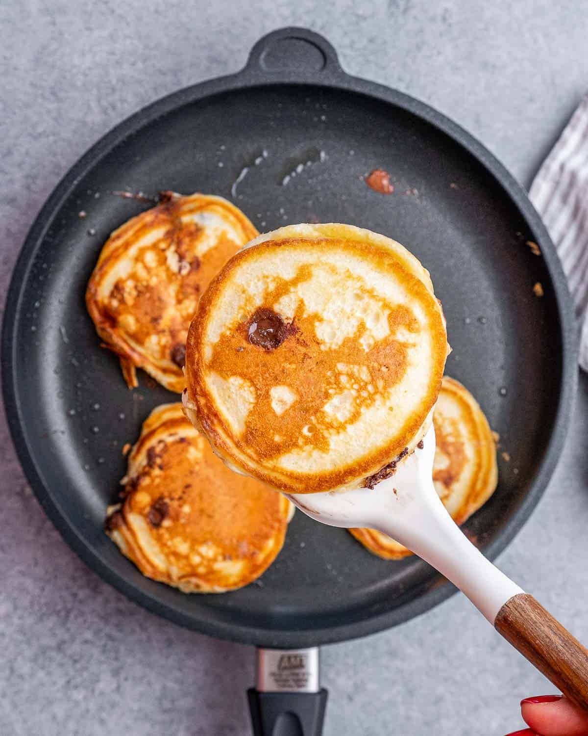 Flipping chocolate chip pancakes in a nonstick skillet.