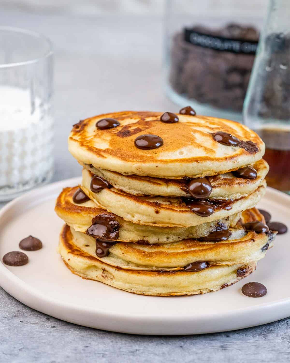 Stack of chocolate chip pancakes on a white plate.