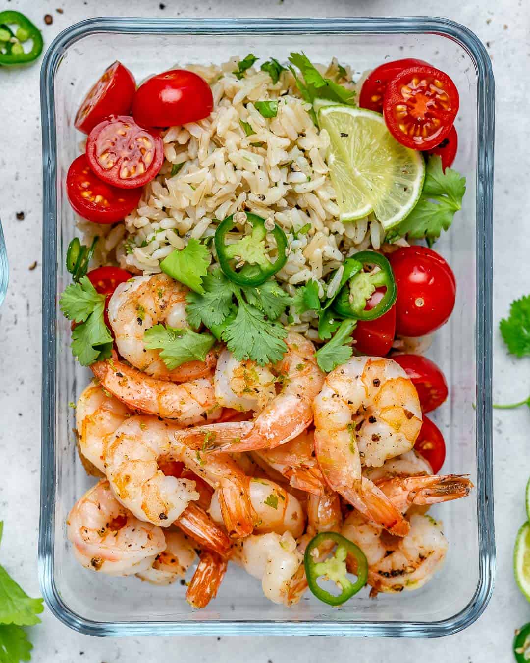 sauteed shrimp in a meal prep bowl with a side or rice and chopped tomatoes.