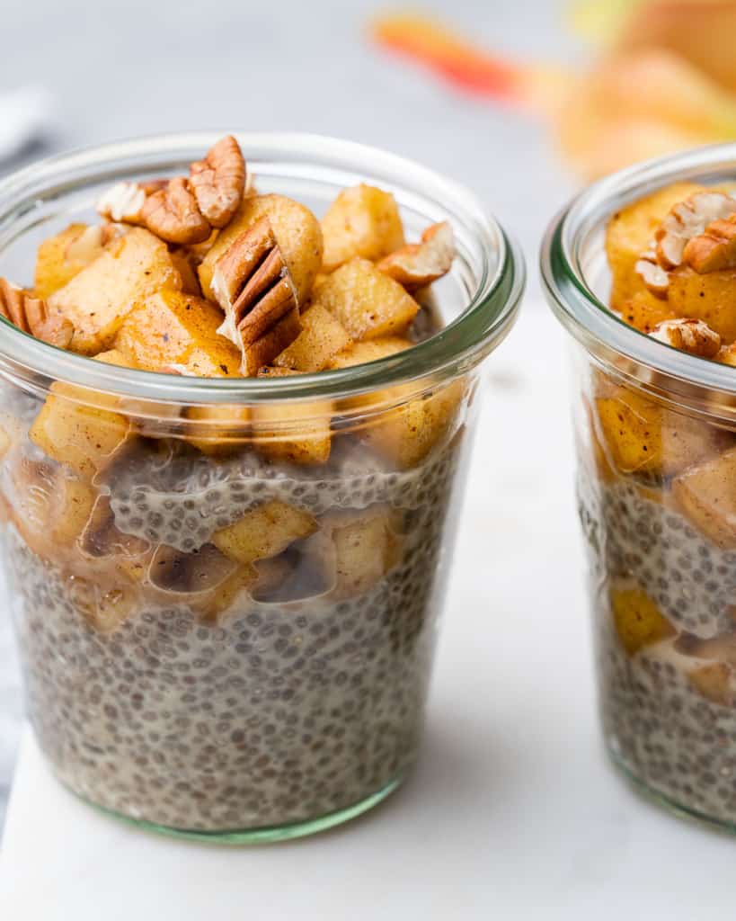 side shot of two jars of chia seed pudding topped with cinammon apples 