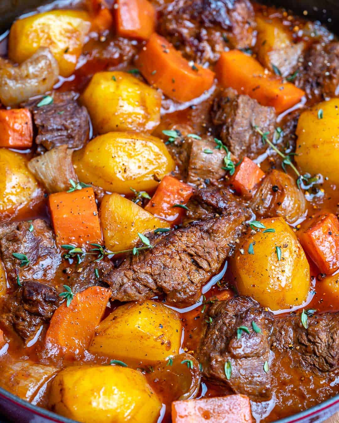 cooked beef stew in a pan with carrots and potatoes.