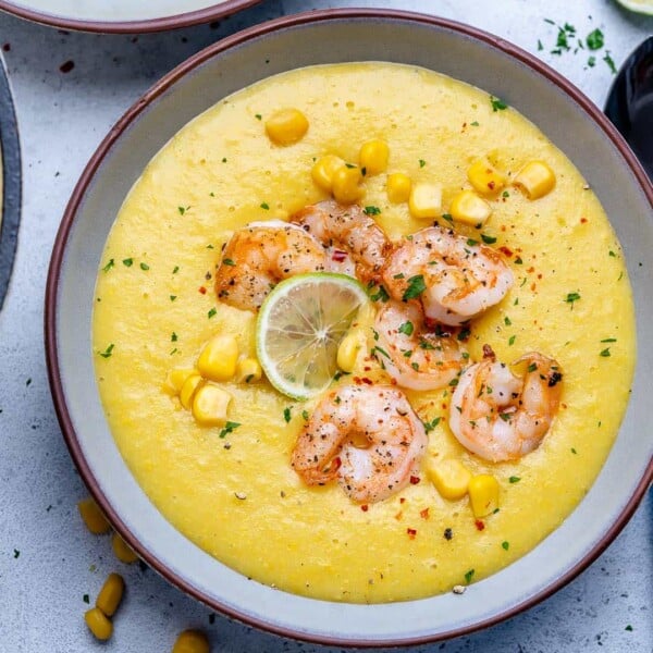 Top view of a round bowl with a yellow color potato and corn soup topped with sauteed shrimps