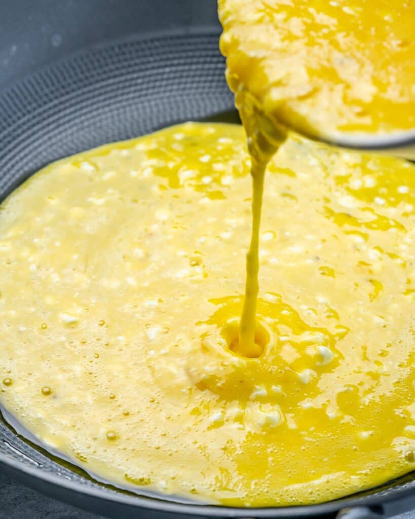 Pouring eggs into a skillet.