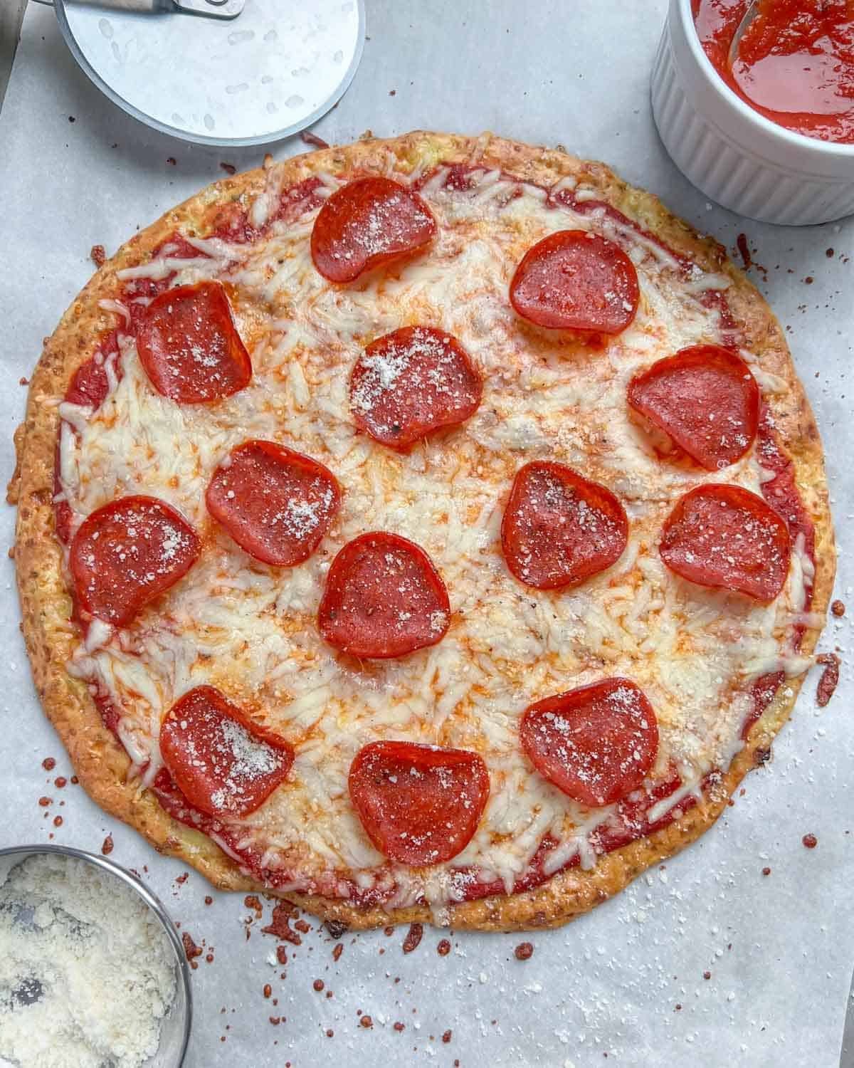 Pizza on a sheet pan, topped with melted cheese and pepperoni slices.