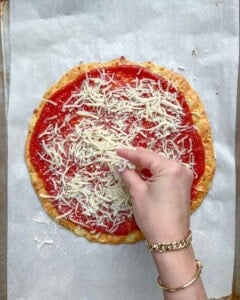 pizza sauce and shredded mozzarella added over pizza crust.