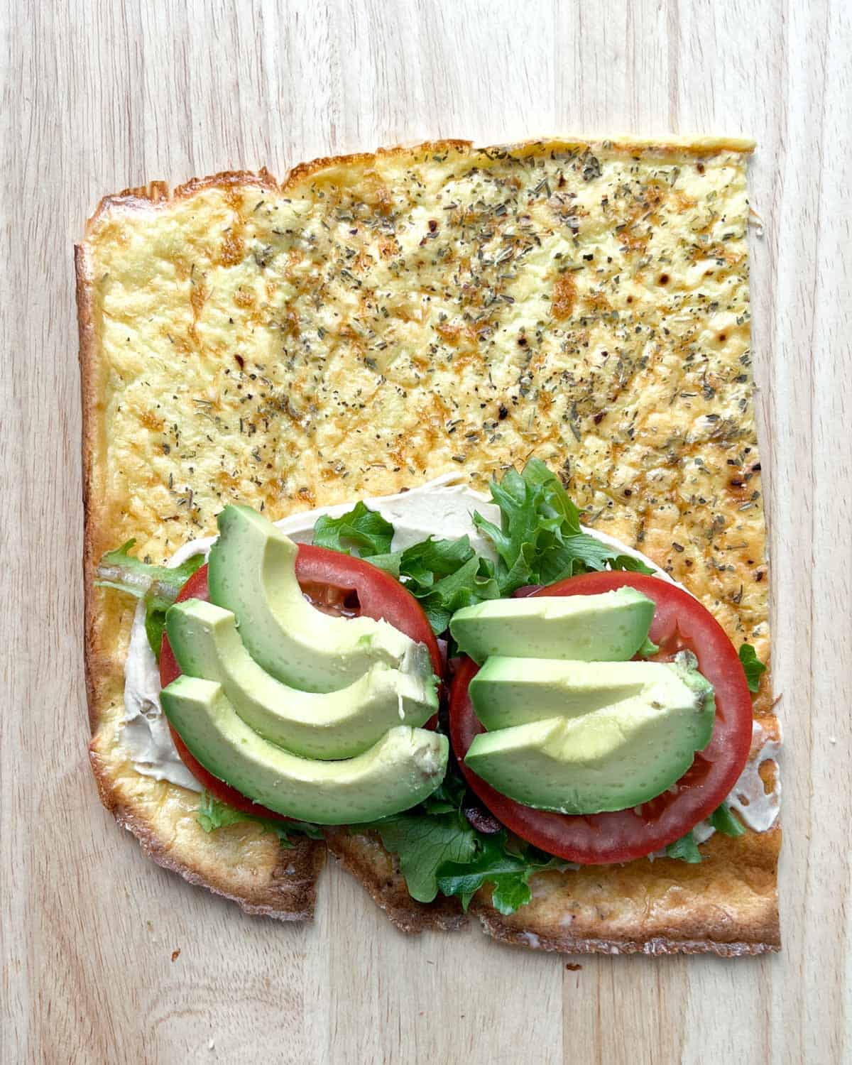 tomatoes and sliced avocados are added over the arugula on the wrap.