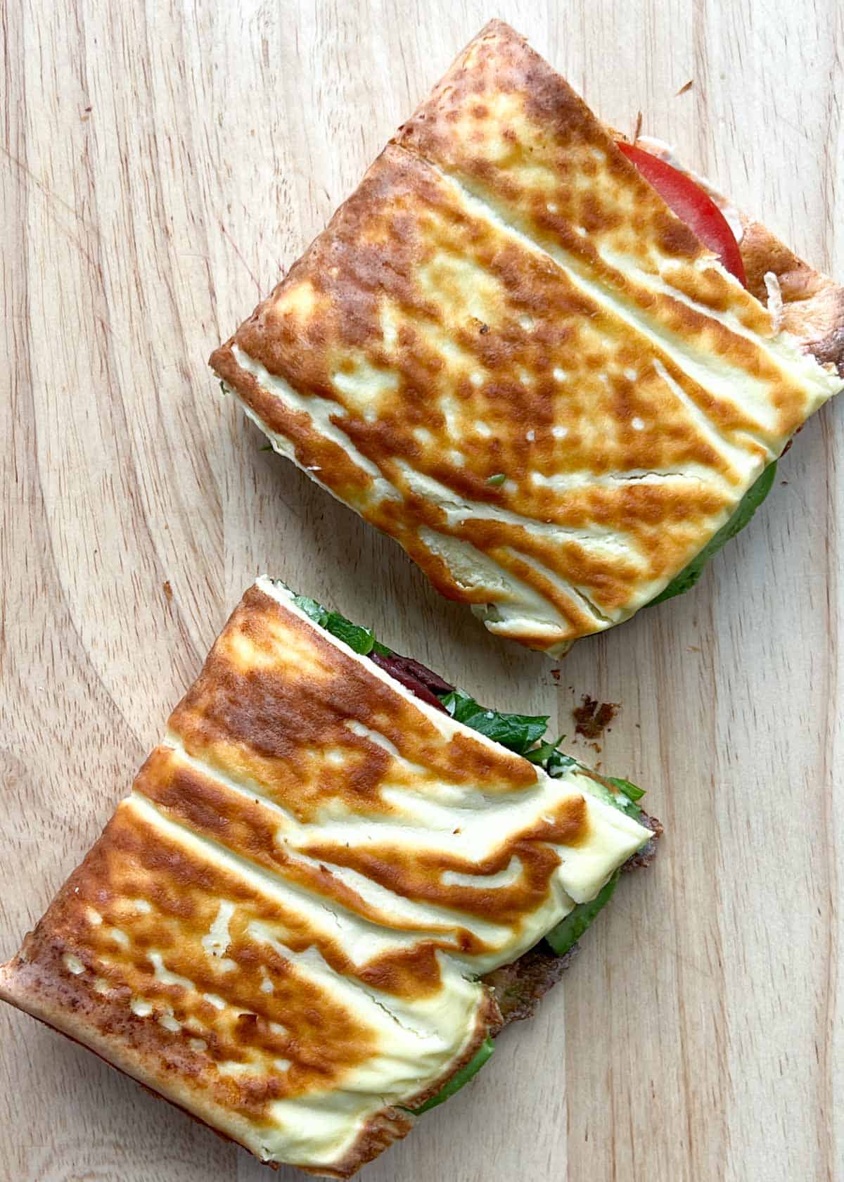 cottage cheese wrap sandwich cut in half on a cutting board.