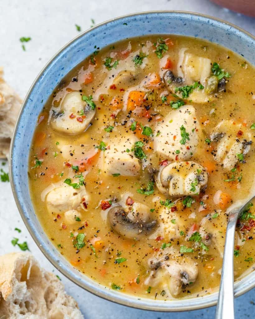 top view of chicken soup in a blue bowl with spoon in it 
