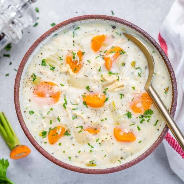 creamy chicken and rice soup in a bowl with a spoon in the bowl.