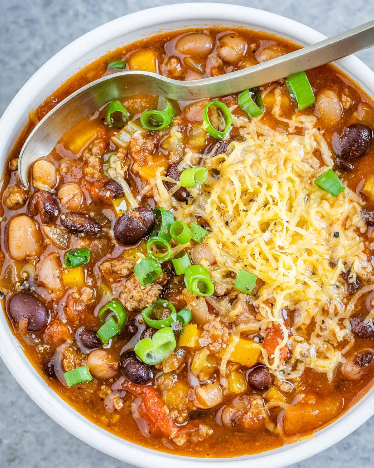 Crockpot chili topped with sliced green onion and shredded cheese.