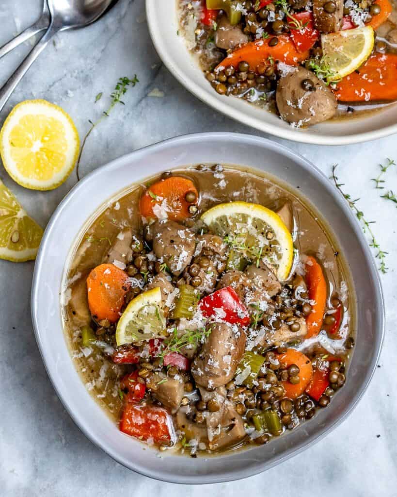 top view of a bowl with lentil and mushroom soup with lemon garnish