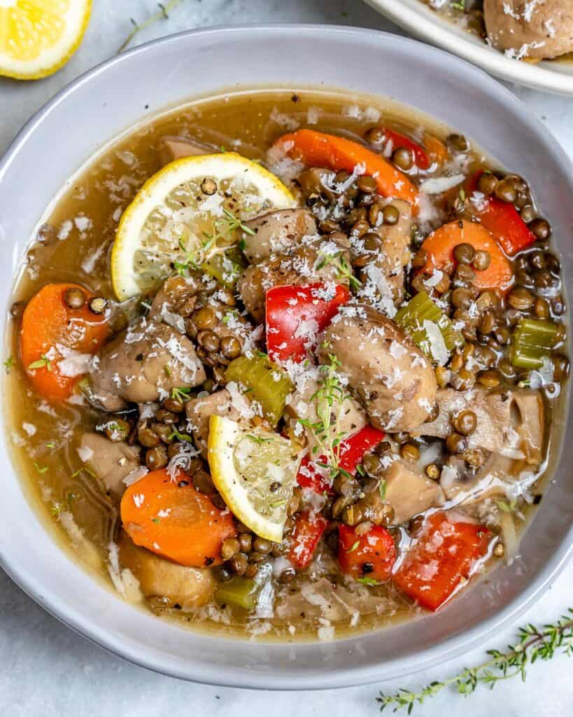 top view of crockpot lentil soup with mushrooms and  carrots with lemon garnish