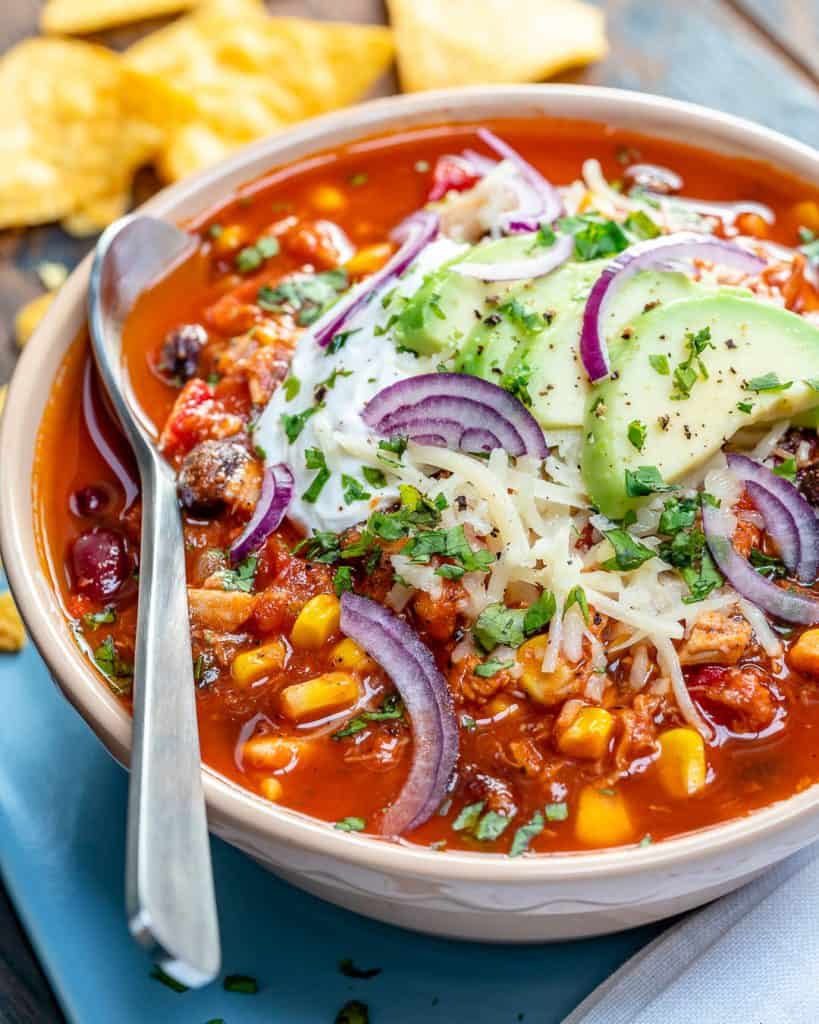side shot of chicken chili in a bowl with spoon on the left side in the bowl