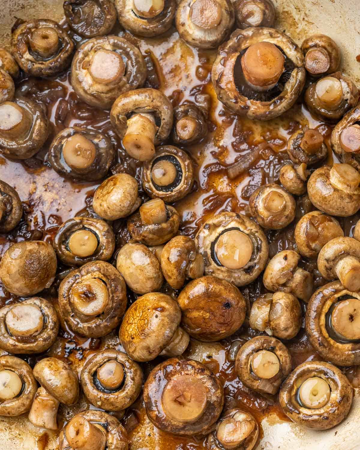 Mushrooms cooking in skillet with beef broth.