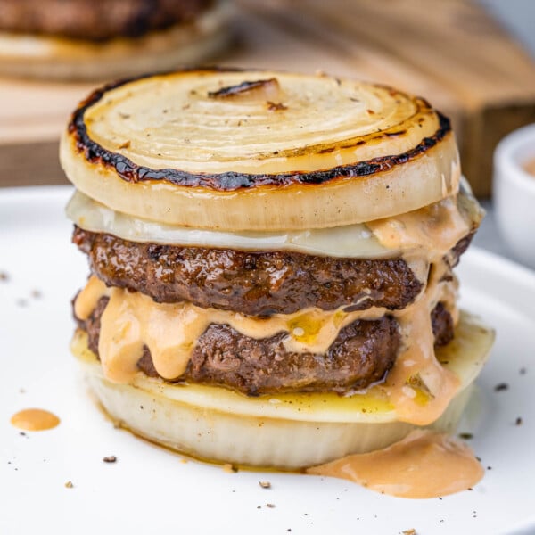 side shot of a dutchman burger which is bunless with sliced onions as buns and melted cheese with in and out sauce