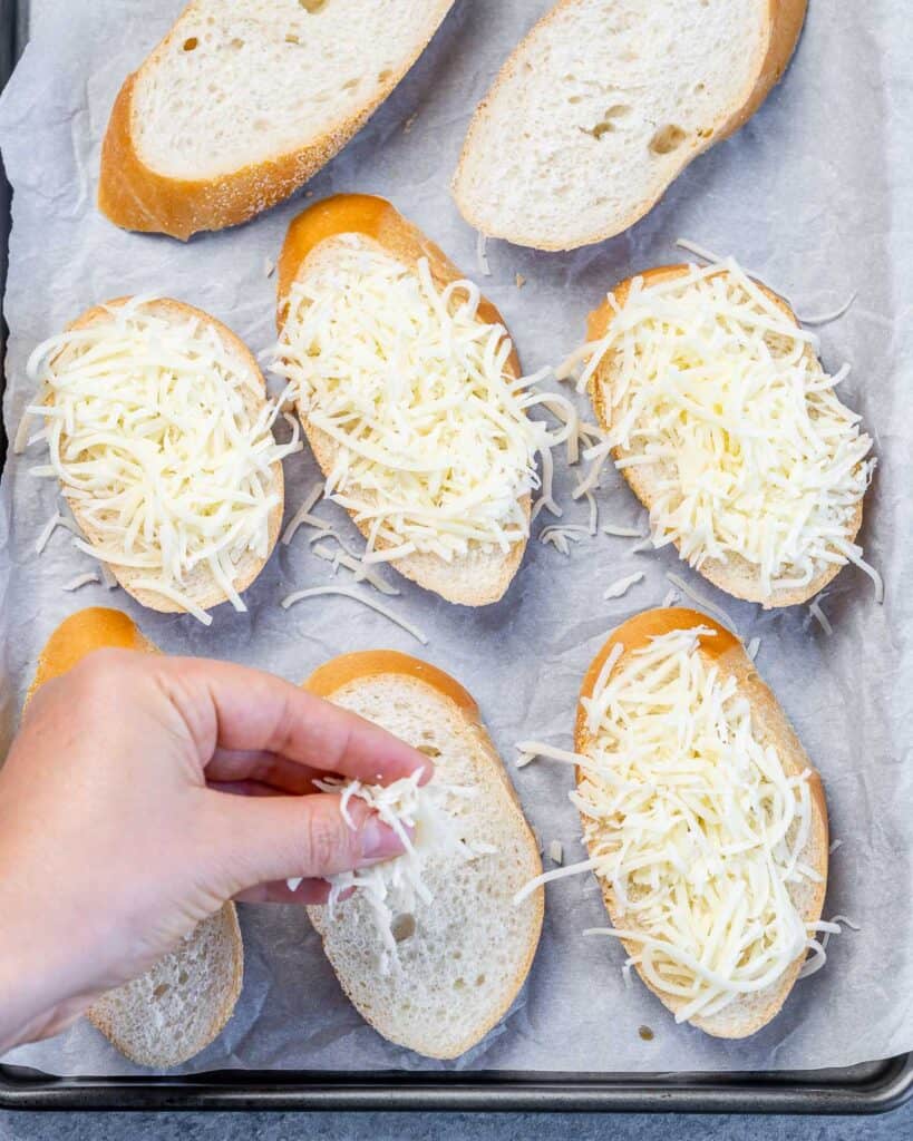 Adding grated cheese to slices of bread.
