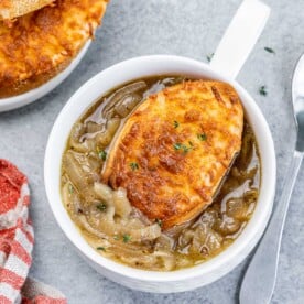 top view of a small bowl of french onion soup topped with cheesy toast over the soup