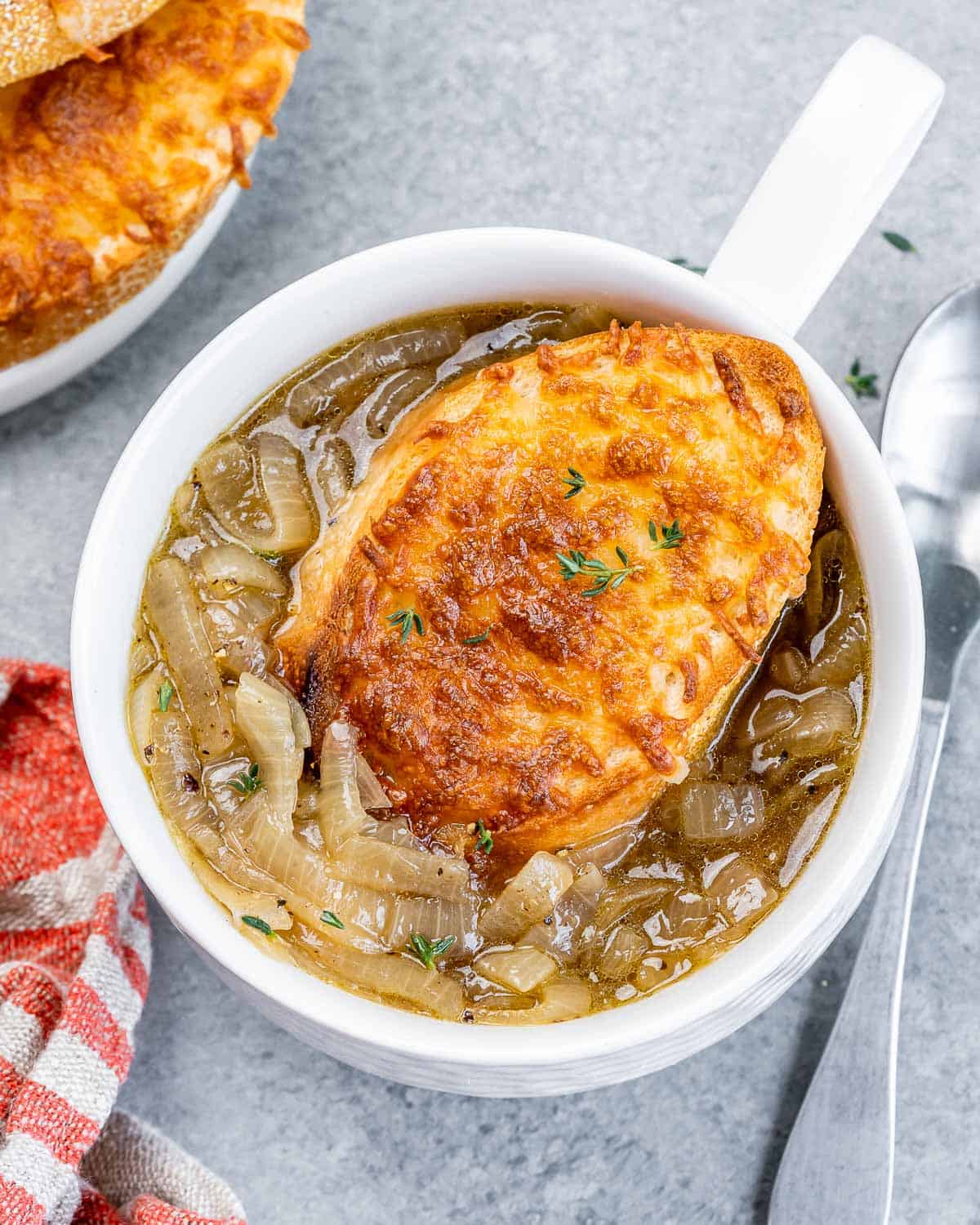 Top view of a small bowl of French onion soup topped with cheesy toast over the soup.