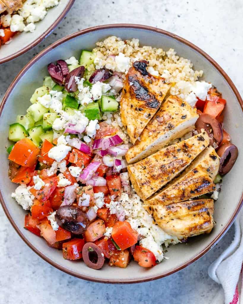 top view grilled chicken with greek inspired salad and quinoa in a bowl