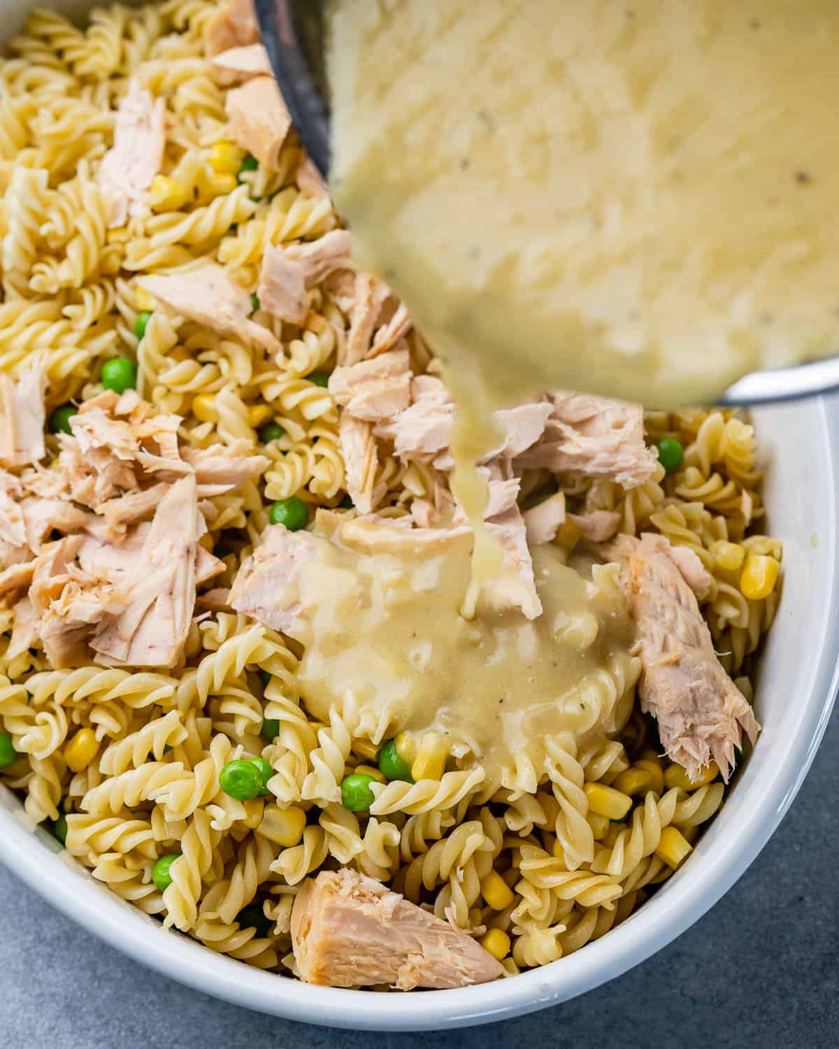 sauce being poured over pasta and tuna 